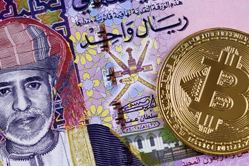 A close up image of a colorful Omani one rial bank note with a golden bitcoin