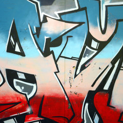 Fragment of graffiti drawings. The old wall decorated with paint stains in the style of street art culture. Colored background texture