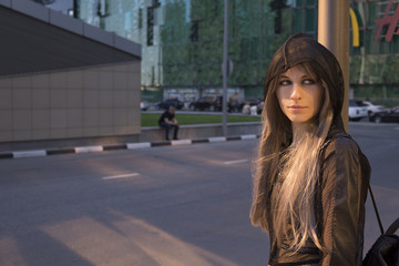 Fototapeta premium Portrait of a fashion urban girl wear black hood in the cityscape in warm light
