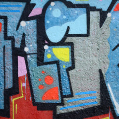 Fragment of graffiti drawings. The old wall decorated with paint stains in the style of street art culture. Colored background texture