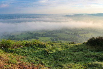 Morning view across the countryside at sunrise with fog and clouds 