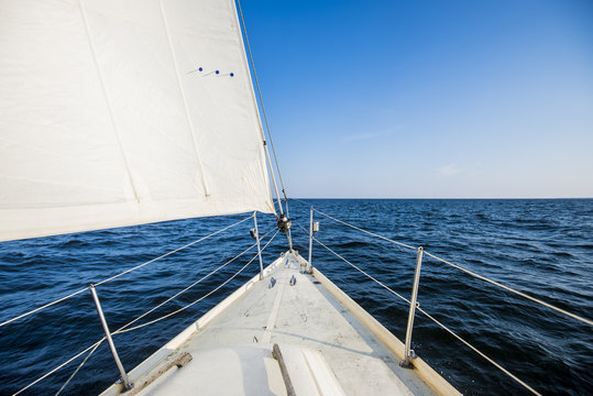 Fototapeta Sailing at sunrise. A view from the yacht's deck to the bow and sails. Baltic sea, Estonia