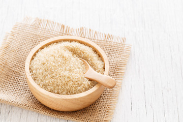 brown sugar and wood spoon in brown bowl on white wooden table