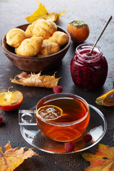 Cup of tea with autumn leaves and cookies on dark background