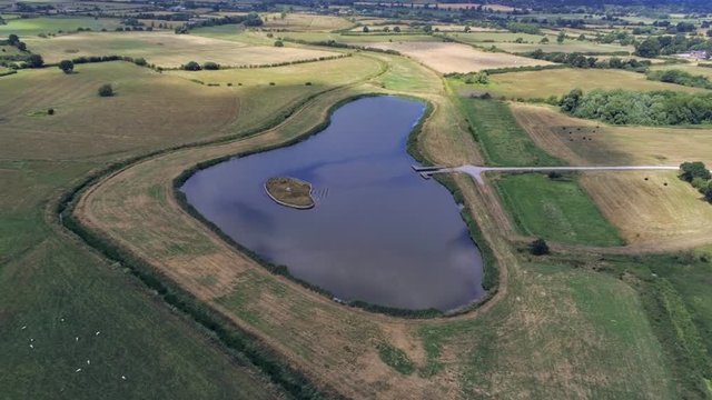 Aerial view, zoom in. Drone panorama of plains and small pond hidden between fields