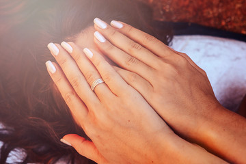 Close-up of girl with stunning dark hair, hiding palms face, hiding her smile.

