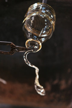 A glassmaker cuts excess glass from a decanter