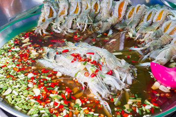 Raw pawns in a chilli, lime juice and spring onioin sauce on a street food stall in Chinatown,...