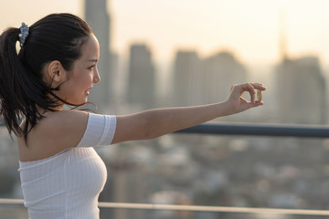 Asian working woman in casual suit holding bitcoin over the cityscape blurred background, business and cryptocurrency concept