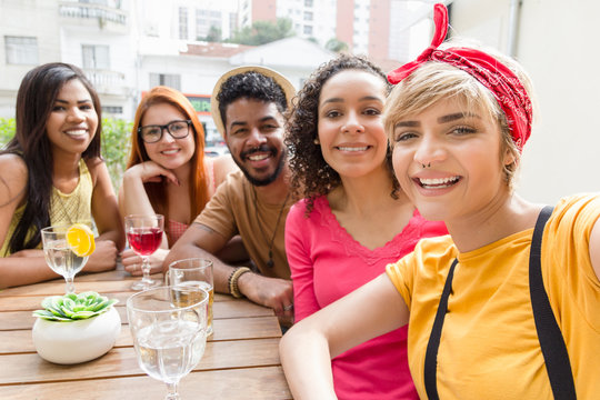 Selfie portrait. Mixed race group socializing in a party at restaurant outside. Summer, warm, friendship, diversity, reunion concept.