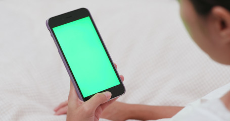 Woman use of mobile phone on bed with chroma key