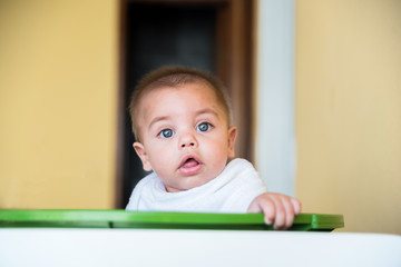 Baby boy playing inside the plastic basin - with cloth diaper on the neck