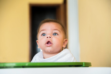 Baby boy playing inside the plastic basin - with cloth diaper on the neck - drooling