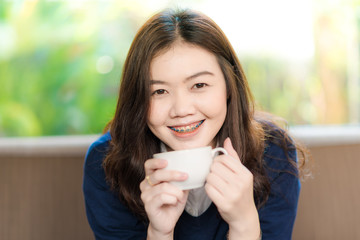 Beautiful asian women drinking hot coffee sitting on vintage sofa
