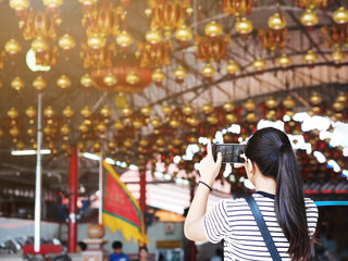 Obraz na płótnie Canvas Back view of Asian girl taking photograph the lamp from mobile phone at China shrine. Chinese new year festival background.