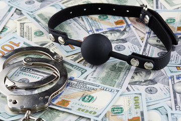 Black gag and handcuffs on american dollars banknotes