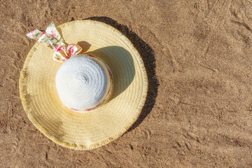 Fototapeta na wymiar Women's hat on the sandy beach. Top view. Background with copy space.