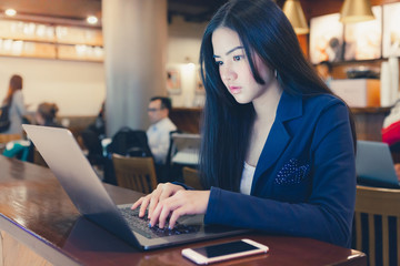 Fototapeta premium Business lady pondering over ideas for her task with laptop in cafe