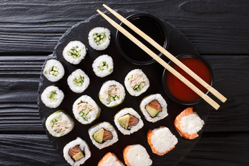 set of freshly prepared rolls with various fillings close-up with sauces on a board. Vertical top view