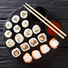 Menu set of Japanese rolls with salmon, tuna, avocado, cucumber served with sauces close-up on a stone. top view