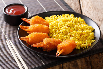 Portion of crab claws fried in breading served with rice and tomato sauce close-up on a plate. horizontal