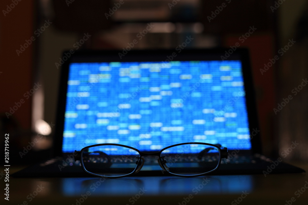 Poster glasses in front of laptop monitor. digital screen displayed blue light code blocks. computer langua