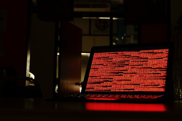 Computer crime. computer with red code in a dark room. Working on binary code technology. binary...
