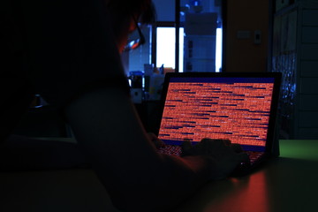 Computer crime. computer with red code in a dark room. Working on binary code technology. binary...