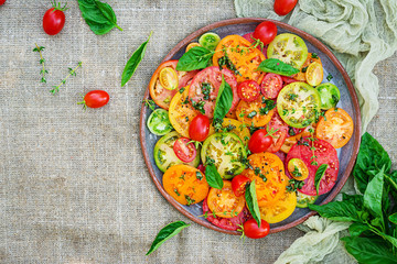 Colored tomato salad with onion and basil. Vegan food. Top view. Flat lay
