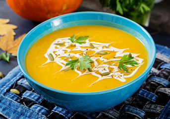 Pumpkin soup in a bowl served with parsley  and pumpkin seeds. Vegan soup.  Thanksgiving day food. Halloween meal.