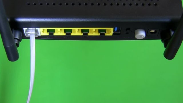 Close up of computer internet router and modem combo isolated on green background.Hand plugging in cables and switching the device on.