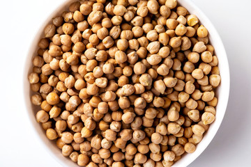 Closeup top view bowl of uncooked chickpeas isolated at white background.