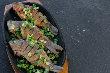 Fried fish carps on a tray sprinkle with green onions.
