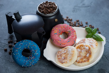 Moka coffee pot with cheesecakes or syrniki and donuts, horizontal shot over blue stone background
