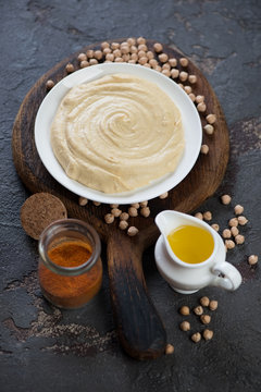 Plate of homemade hummus with raw chickpeas, olive oil and spices, studio shot, selective focus