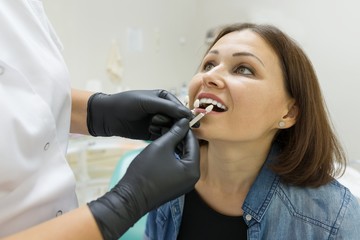 Adult woman sitting in chair of dentist in clinic and preparing for procedure. Medicine, dentistry and healthcare concept.