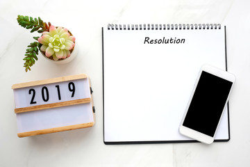 2019 resolution on blank notebook paper, smart phone with blank screen on white marble background, 2019 new year mock up, template, flat lay