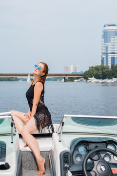 Image of young amazing red hair attractive girl in sunglasses wearing black T-shirt with fringe on the yacht. Carefree time on yacht. Beautiful woman on her private yacht 