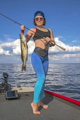 Happy fisher woman with zander fish trophy at the boat with fish finder, echolot, sonar