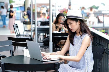 Young asian woman using laptop computer sitting at cafe outdoors, people and technology, lifestyles, education, working outdoors, business concept