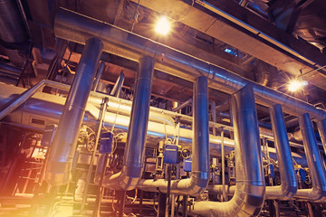 Equipment, cables and piping as found inside of a modern industrial power plant. Industrial zone, Steel pipelines, valves, cables and walkways