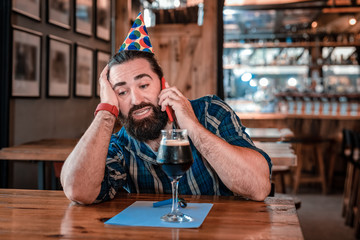 Calling friends. Handsome mature man calling his best friends waiting for them in pub on his birthday