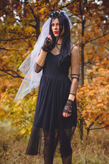 Halloween Witch in a dark forest. Beautiful young woman in witches modern dress . Halloween art design. Dark theme For Halloween Concept 