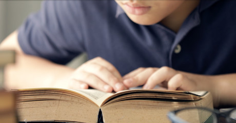 Close up hand of asian boy reading a book .