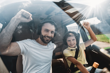 We are ready. Portrait of cheerful unshaven man and optimistic child gesticulating hands while...