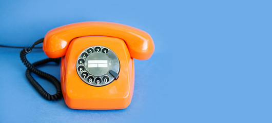 Retro phone orange color, vintage handset receiver on blue background. copy space