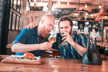 Football lovers. Two football lovers drinking craft dark beer and eating burgers while celebrating...