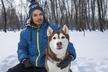 Christmas happy teenager boy playing with white Husky dog in winter day, dog and child on snow
