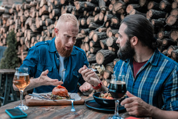 Food and alcohol. Two bearded man feeling relaxed while eating and drinking alcohol on Sunday night