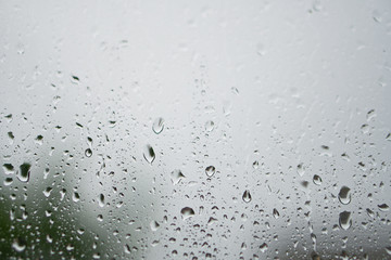 Rainy, autumn weather outside the window. Drops of water on the glass on a blurred background. Romantic grubby topic. Stock photo for design